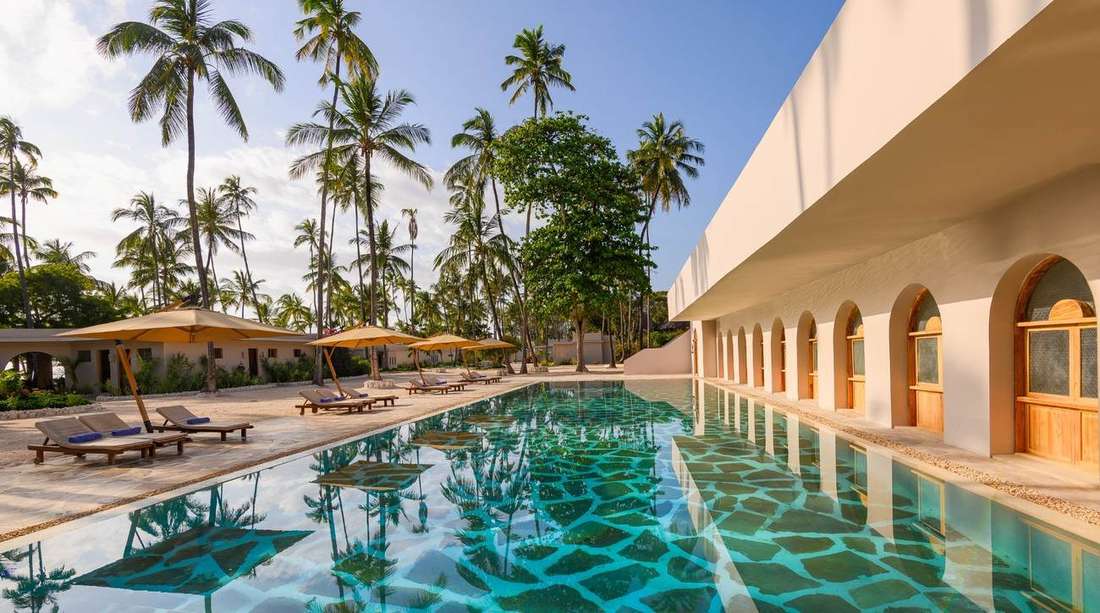 Resort swimming pool framed by arches and palms